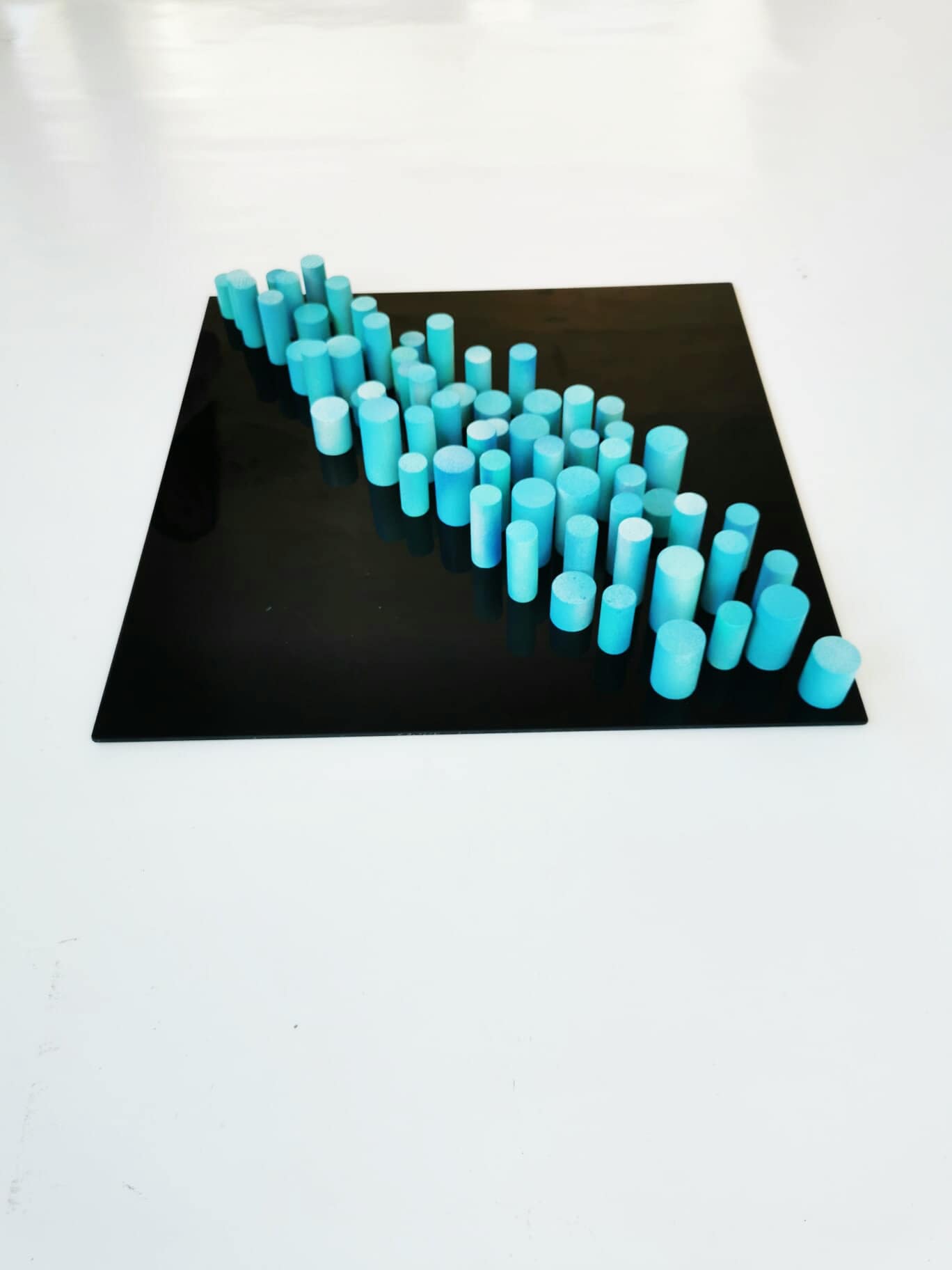 Sculpture wall art, 3D art. Different wood wall art in bold colors. Blue and turquoise dowels . Modern design in black acrylic glass base.©