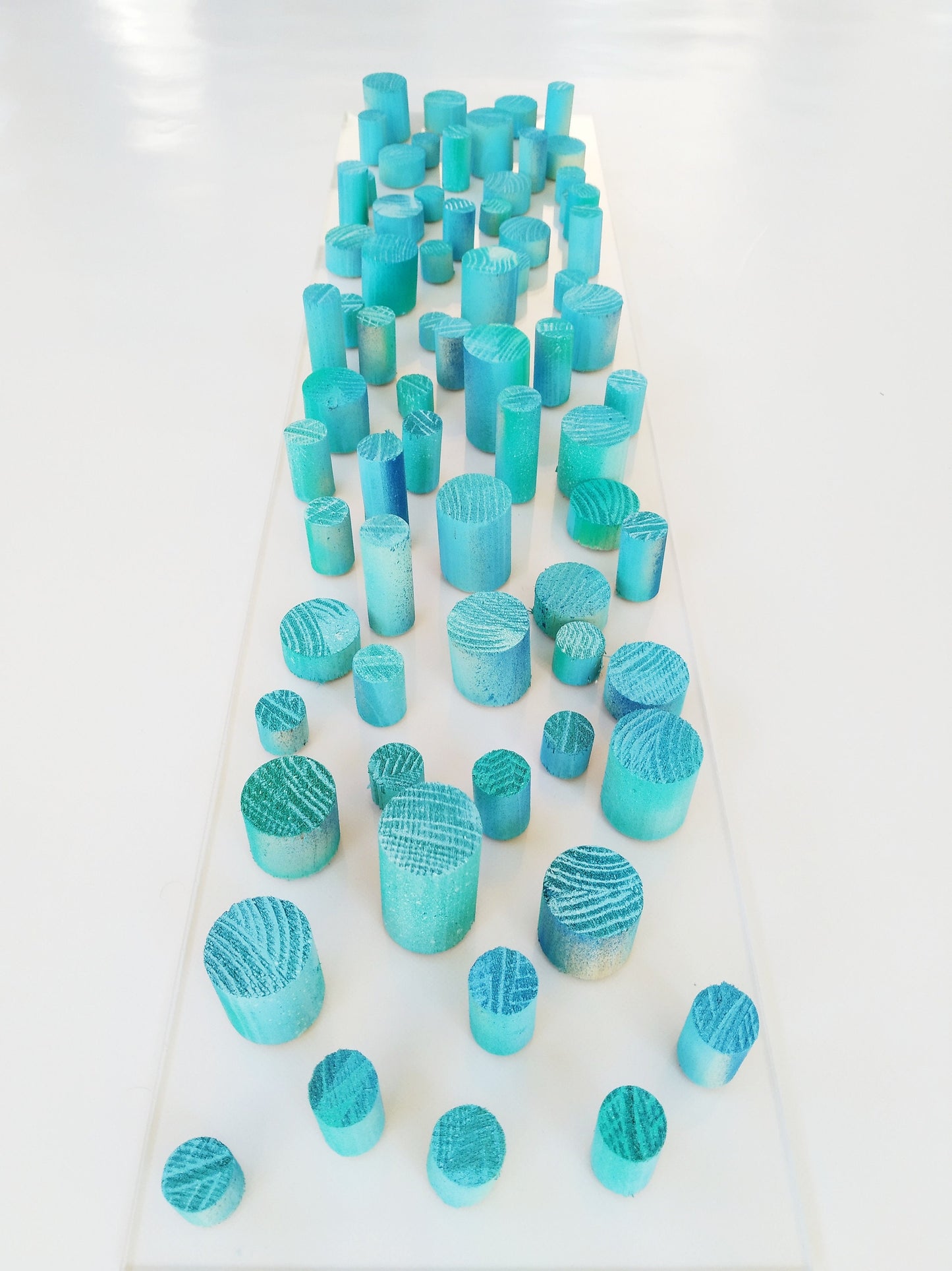 Unique© different piece of art in wood. Blue hand painted wooden dowels in recycled wood. Ocean, sea, beach, coastal theme. Transparent base