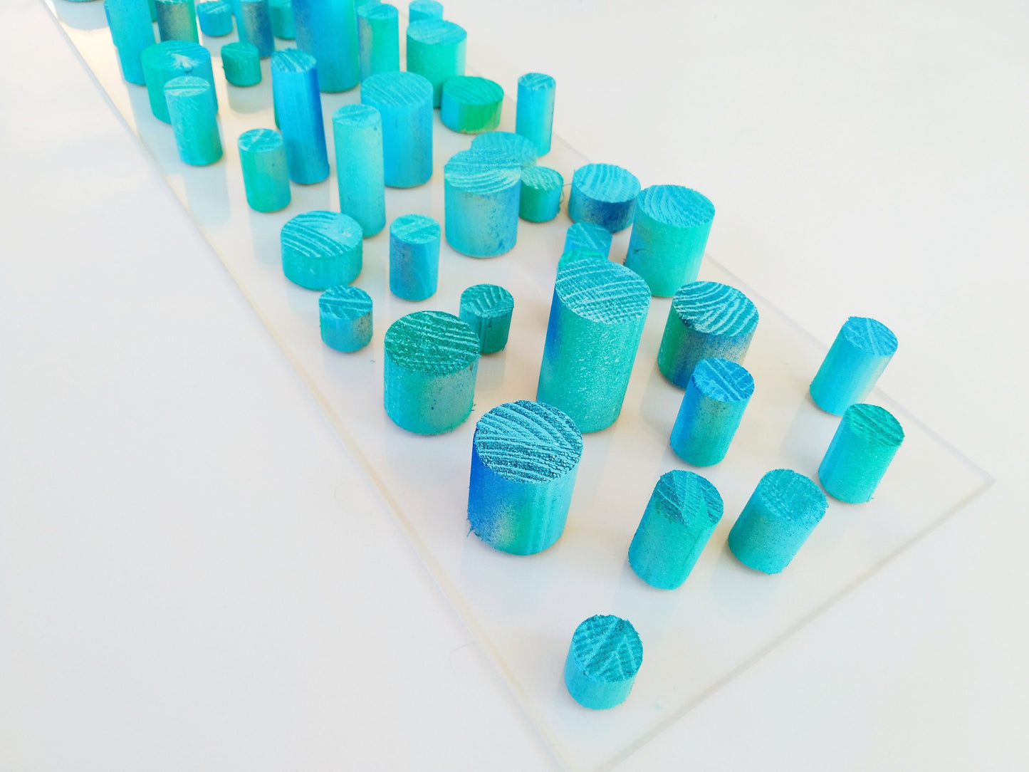 Unique© different piece of art in wood. Blue hand painted wooden dowels in recycled wood. Ocean, sea, beach, coastal theme. Transparent base