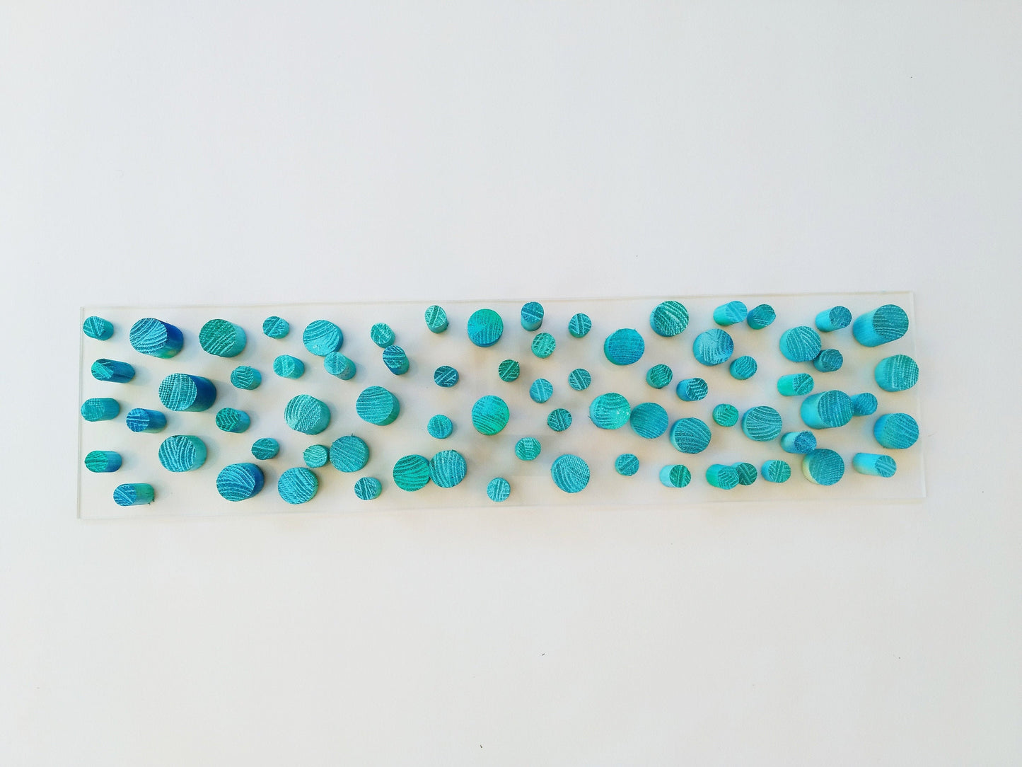 Unique© different piece of art in wood. Blue hand painted wooden dowels in recycled wood. Ocean, sea, beach, coastal theme. Transparent base