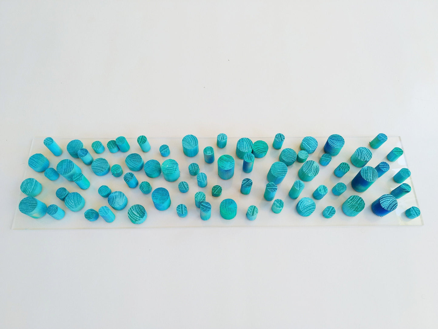 Unique© different piece of art in wood. Blue hand painted wooden dowels in recycled wood. Ocean, sea, beach, coastal theme. Transparent base