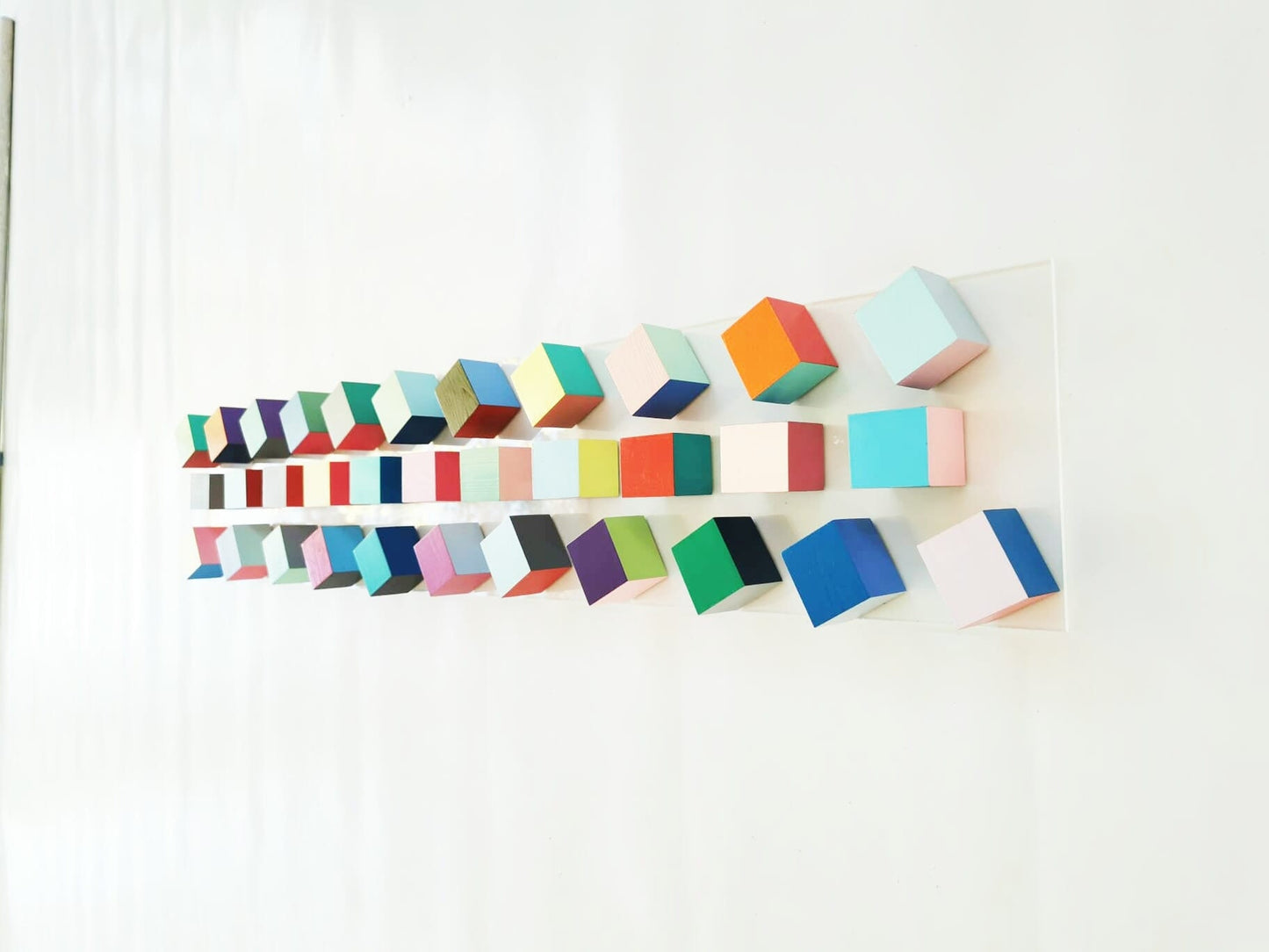 Geometric wall art in happy, joyful colors. 3D art installation on transparent acrylic glass base. Pop art sculpture, block wall sculpture