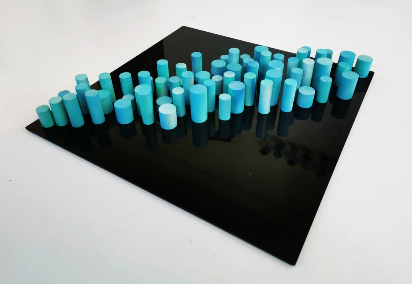 Sculpture wall art, 3D art. Different wood wall art in bold colors. Blue and turquoise dowels . Modern design in black acrylic glass base.©