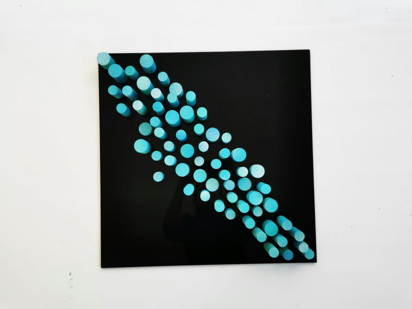 Sculpture wall art, 3D art. Different wood wall art in bold colors. Blue and turquoise dowels . Modern design in black acrylic glass base.©