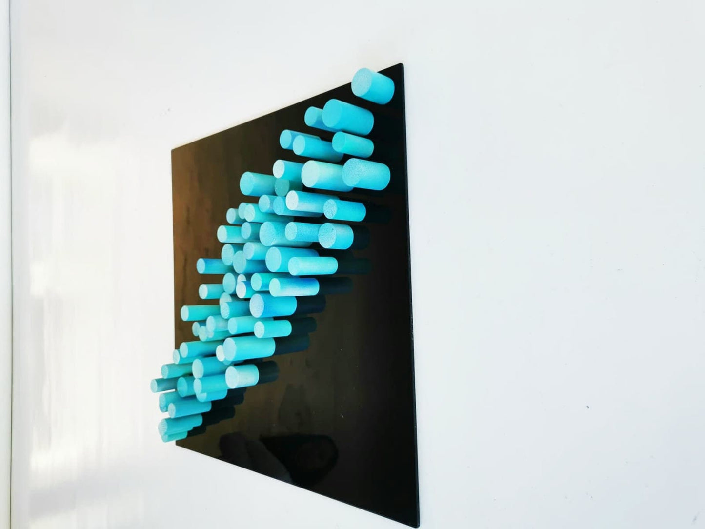 Sculpture wall art, 3D art. Different wood wall art in bold colors. Blue and turquoise dowels . Modern design in black acrylic glass base.©